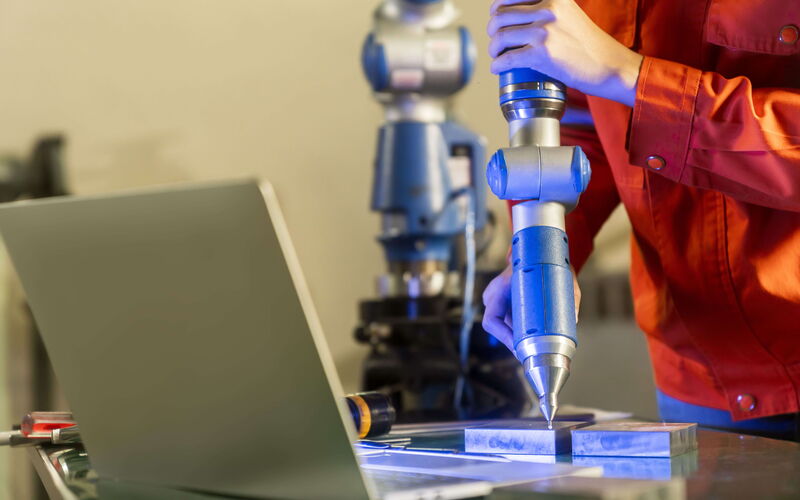 Engineer performs a three-dimensional coordinate measurement on a measuring machine with manipulator arm