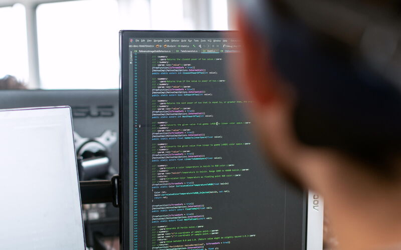 Engineer in black shirt sitting in front of computer monitor